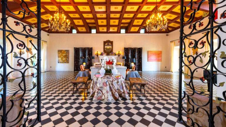 Opulent ballroom with checkered marble floors at Deering Estate, furnished with small luxurious tables and seats for a private event.