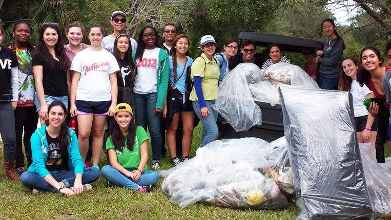 Group of young volunteers gathered together with all of the trash they cleaned up