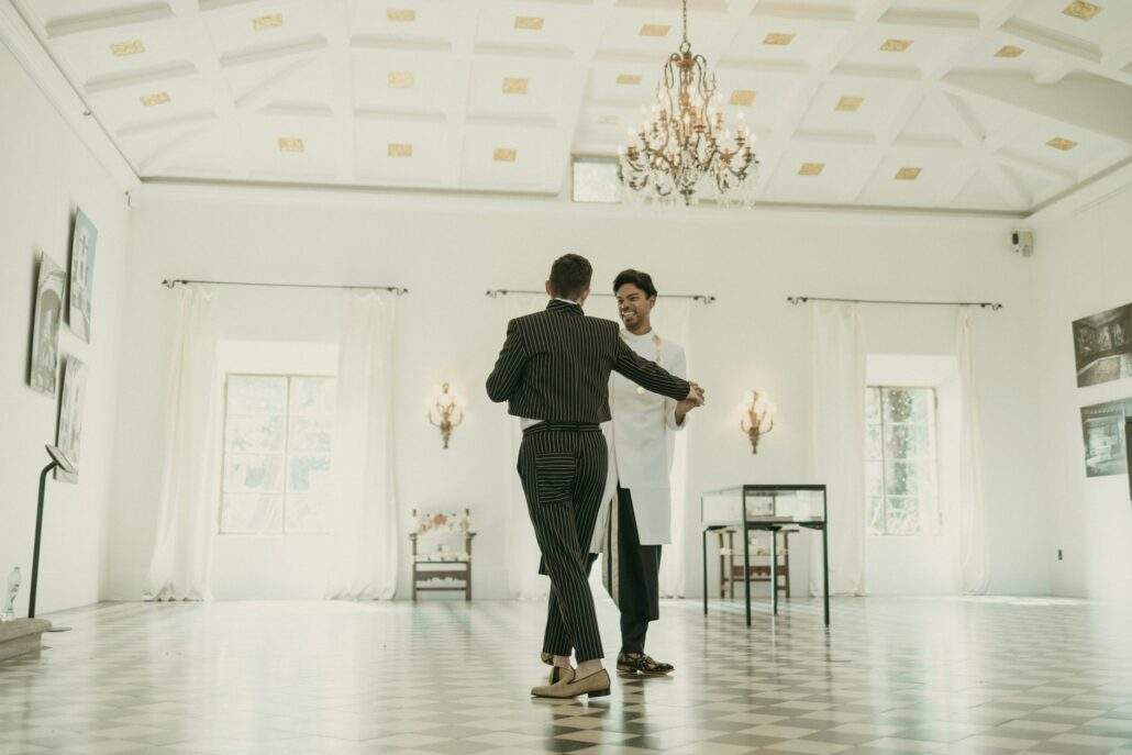Grooms posing for a picture inside Deering Estate's Stone House grand hall ballroom