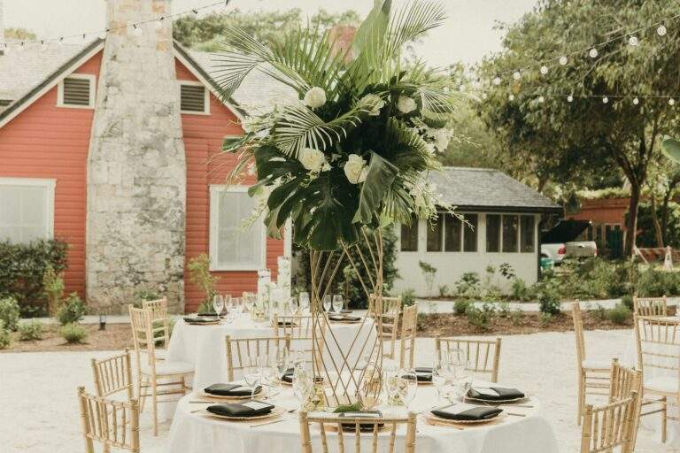 Detail shot of a table with a coastal floral arrangement in Deering Estate's historic Courtyard with the Richmond Cottage Museum in the background