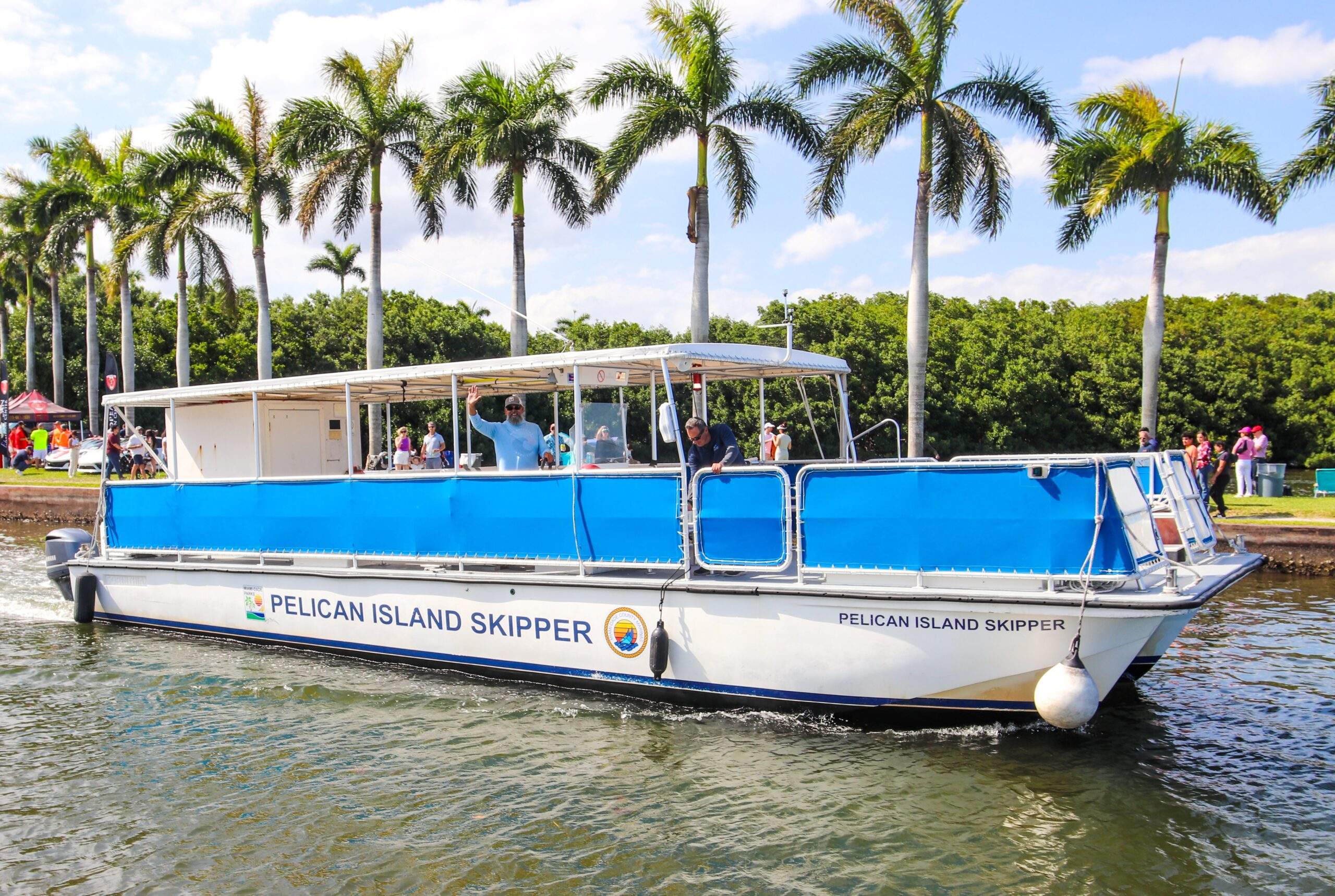 A white boat with blue sides named the Pelican Island Skipper departs from the Deering Estate boat basin.