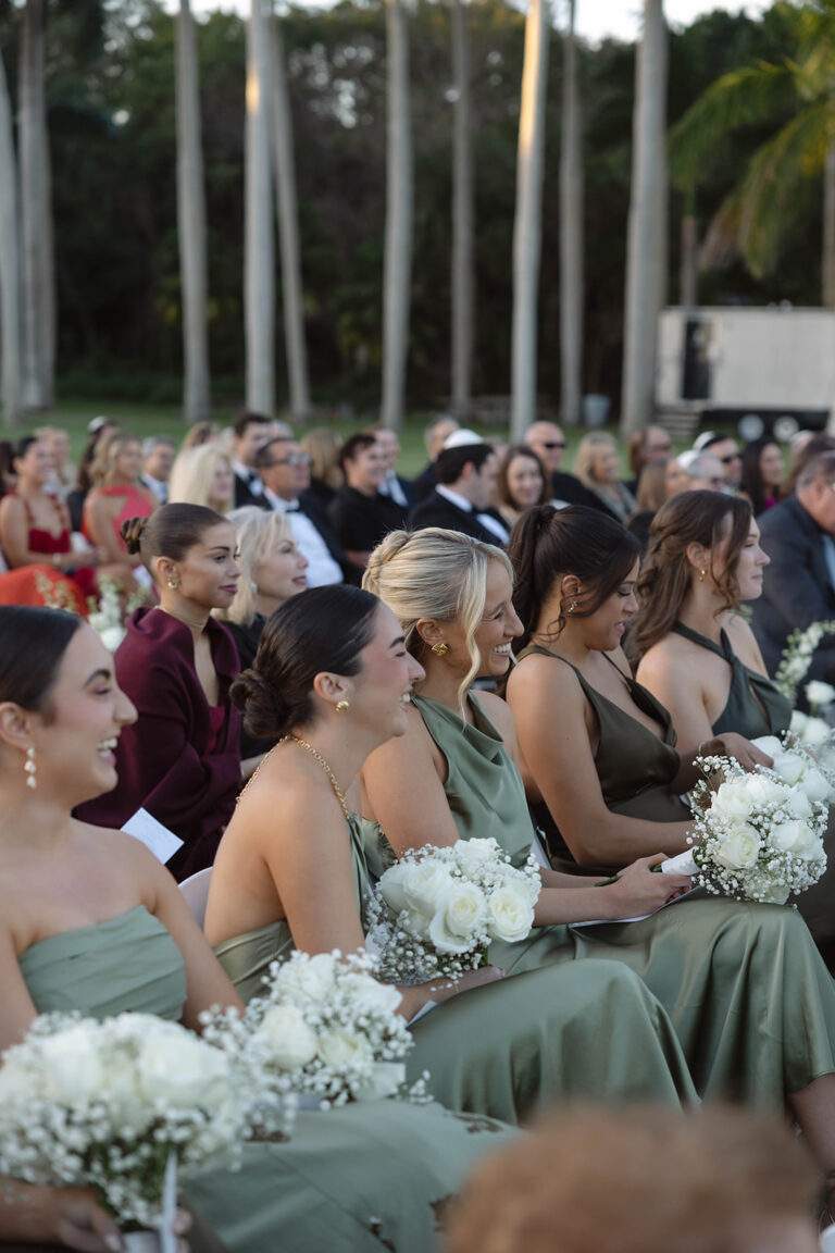 A focus on the bridesmades in sage green dresses holding bouquets at the Annie & Henry wedding at Deering Estate in Miami, Florida.