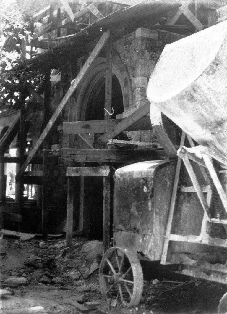 Charles Deering's Stone House in the middle of construction during the early 1900's, covered in wood scaffolding, with a concrete truck in the foreground.