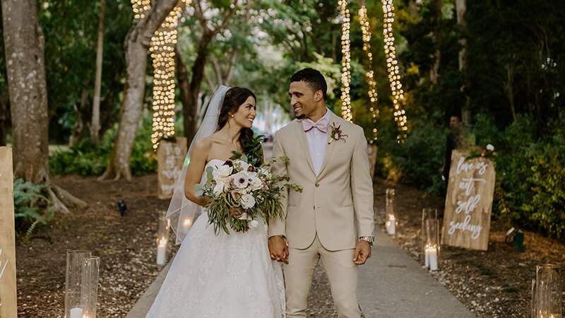 Bride and groom walking together down the main pathway surrounded by festively lit trees