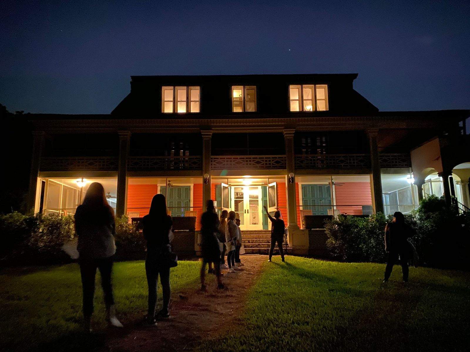Eight people on a Deering Estate ghost tour at night in front of the Richmond Cottage.